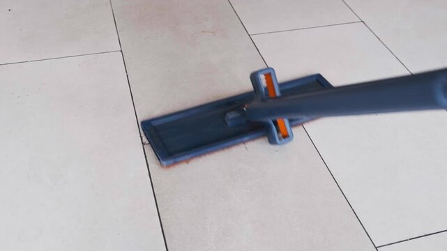 Close Up of a Flat Mop Cleaning and Washing Tiled Floor in a Room
