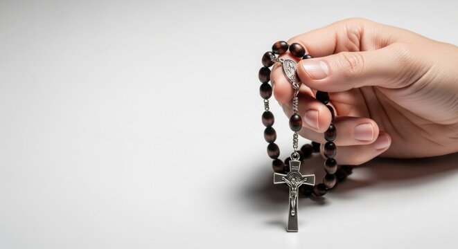 Closeup of a hand holding a rosary with a crucifix.