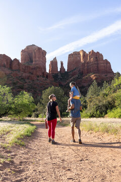 Family of three walking along outdoor hiking trail with mountain view