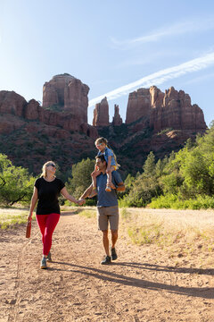 Family of three laughing on outdoors hiking trail