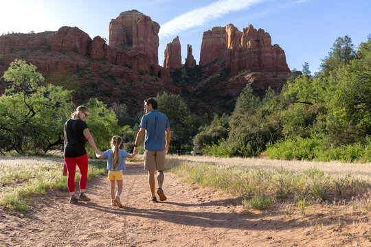 Family of three walking away on hiking trail with mountain view
