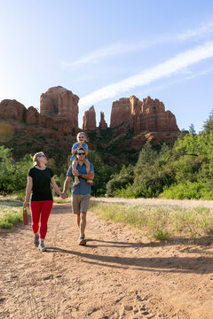 Family of three walking outdoor wilderness hiking trail mountain view
