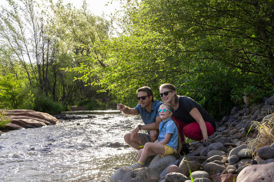 Family of three spotting something outdoors by wilderness stream