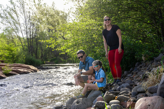Family of three enjoying outdoors by wilderness stream