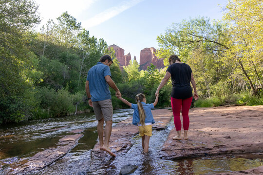 Family of three walk barefoot in wilderness creek