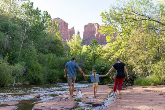 Family of three walk barefoot near wilderness creek
