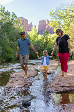 Family of three walking barefoot near outdoors in stream