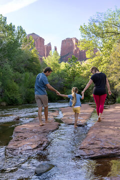 Family of three walk barefoot in creek outdoors