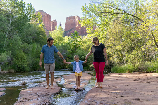 Family of three approaching barefoot near wilderness creek