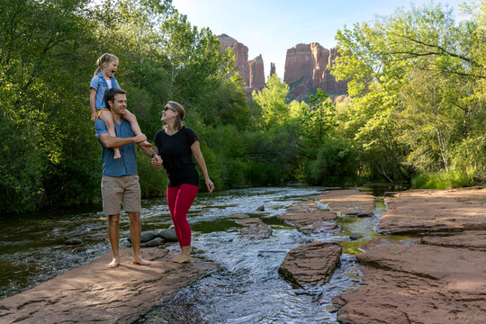 Family of three enjoying outdoors near rocky stream