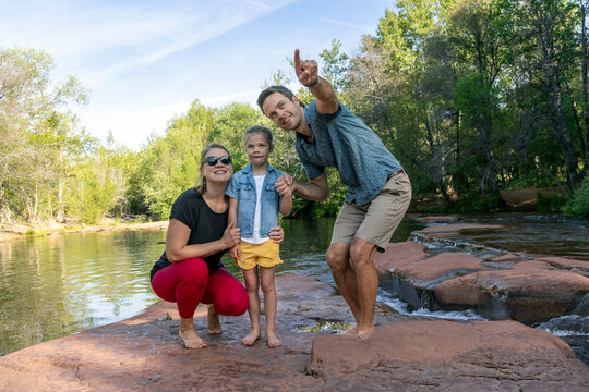 Dad points to family outdoors by natural stream