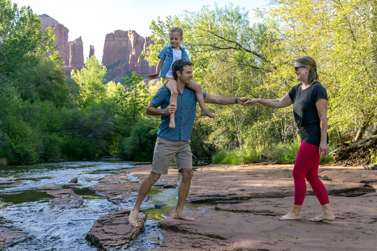 Family of three holding hand by rocky stream