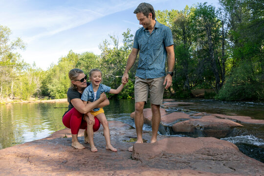 Family of three laughing enjoying outdoors by creek