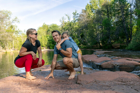 Family of three laughing enjoying outdoors by stream