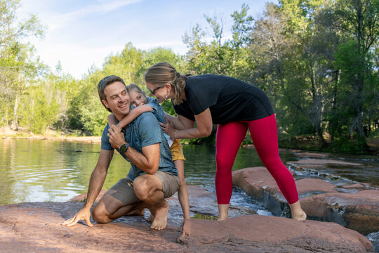 Family of three laughing enjoying outdoors rocky creek