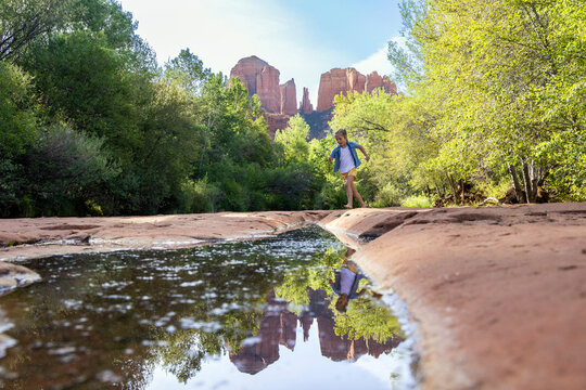 Lone girl playing in wilderness by reflecting pool