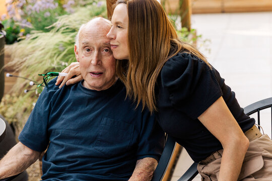 Adult daughter comforting elderly father outdoors