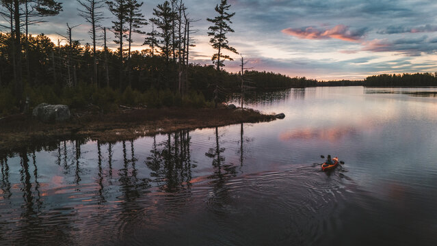 One person kayaking on a calm pond at dusk, Machias Lake, Maine
