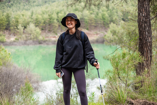 Happy young woman hiking in the forest by a lake