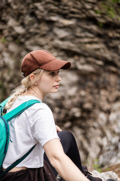 Young female hiker rests against a rock face