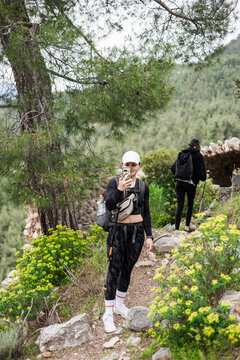 Woman taking a picture while hiking a mountain path