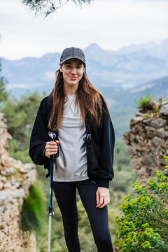 Happy female hiker with pole poses for portrait in the mountains