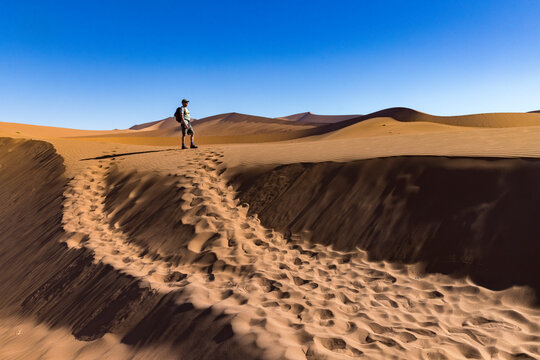 Hiker looks out over desert sand dunes