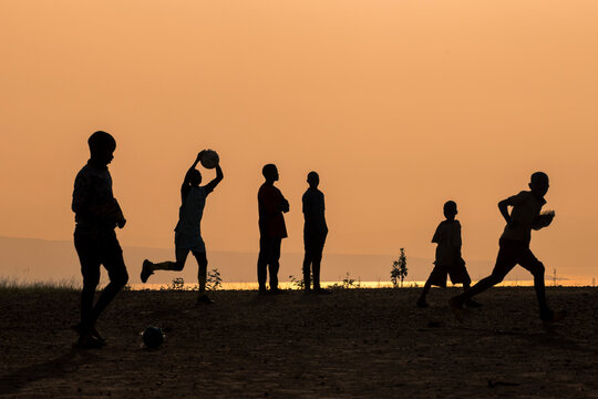 Silhouettes of boys playing soccer during sunset