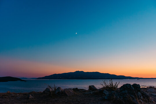Crescent moon shines over Corfu island at blue hour from Albania