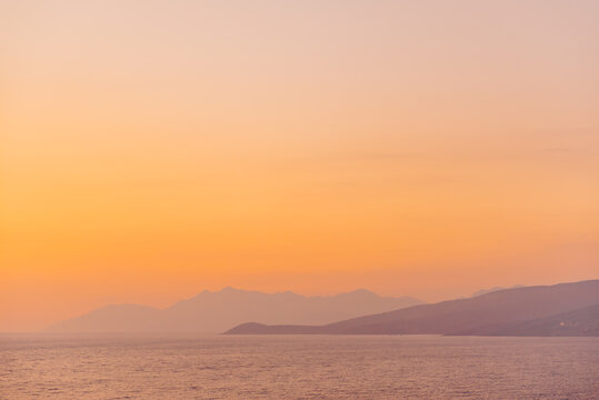 Hazy mountains and sea with golden hour sky in Albania towards Sarand&euml;
