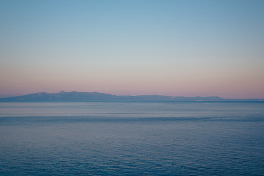 View toward Corfu across calm Ionian Sea at sunset from Qeparo