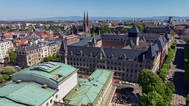 Drone flying over Theatre National de Strasbourg with Les Jardins d'Arcadie senior living community and St. Paul church in background, France. Aerial forward