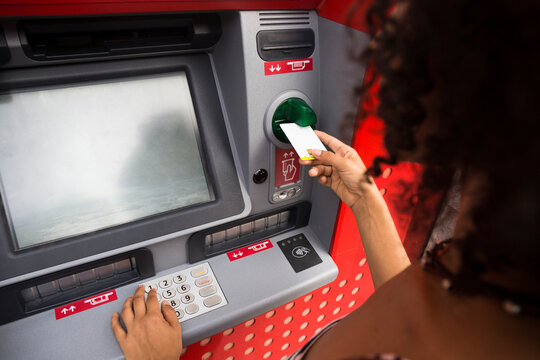 Woman pushing credit card at cash dispenser