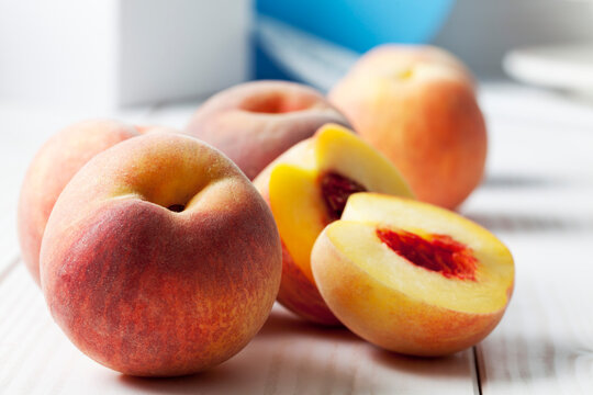 Whole and sliced peaches (Prunus persica) on white wooden table