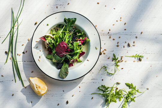 Spring salad of baby spinach, herbs, arugula and lettuce on plate, lemon