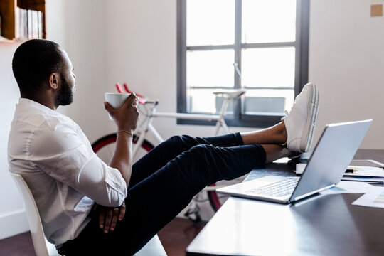 Relaxed man in home office with feet on desk