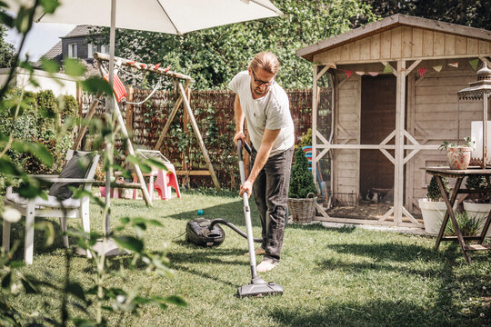 Man hoovering lawn in garden