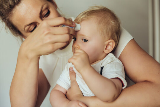Mother using a skin thermometer to take baby?s temperature