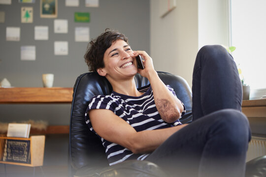 Happy woman talking on cell phone at home