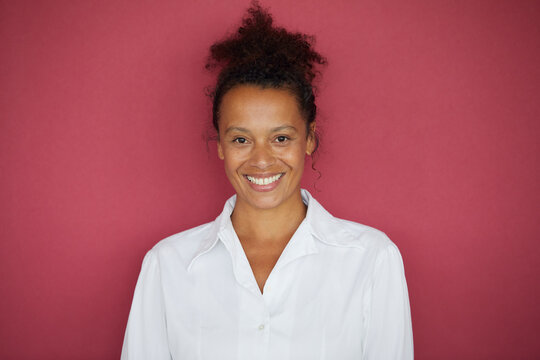 Portrait of smiling businesswoman against red background