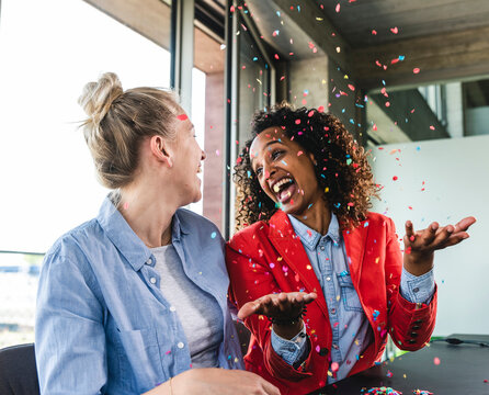 Young busniesswomen celebrating success, throwing confetti