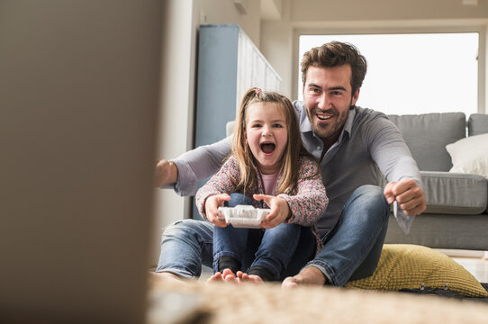 Young man and little girl playing computer game with gaming console