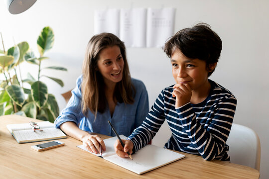 Female tutor helping boy in writing homework at home