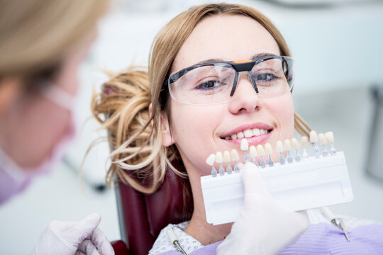 Woman at the dentist choosing color for teeth whitening