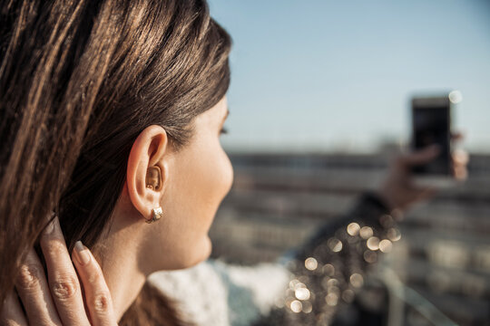Young woman with hearing aid taking selfie with smartphone