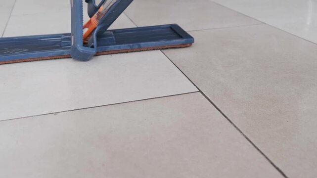 Close Up of a Flat Mop Cleaning and Washing Tiled Floor in a Room