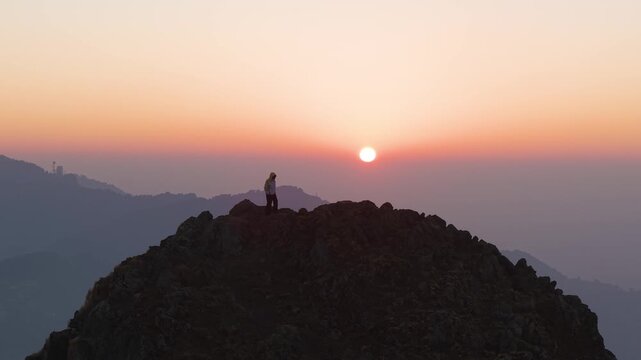 4K cinematic drone footage of a boy enjoying a vibrant Himalayan sunrise from a mountain peak in Uttarakhand.