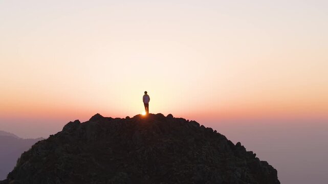 4K cinematic sunrise landscape with a boy silhouetted on a rocky mountain peak in Uttarakhand.