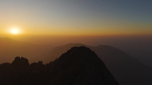 4K scenic drone footage capturing sunrise colors over the Himalayas with a traveler on rocky terrain.