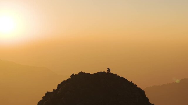 4K aerial footage of a boy enjoying morning sunlight on a dramatic mountain peak in Uttarakhand.